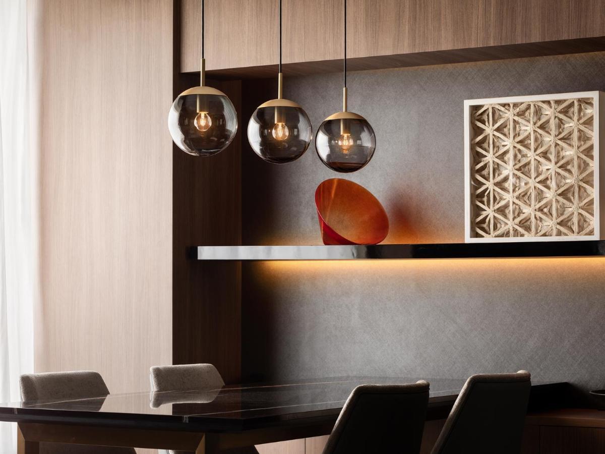 Mitsui Garden Hotel Roppongi Tokyo Premier Εξωτερικό φωτογραφία The photo depicts a modern interior design scene. It features a sleek dining area with a dark wooden table and comfortable chairs. Above the table, there are three pendant lights with glass shades that provide ambient lighting. A geometric art piece 