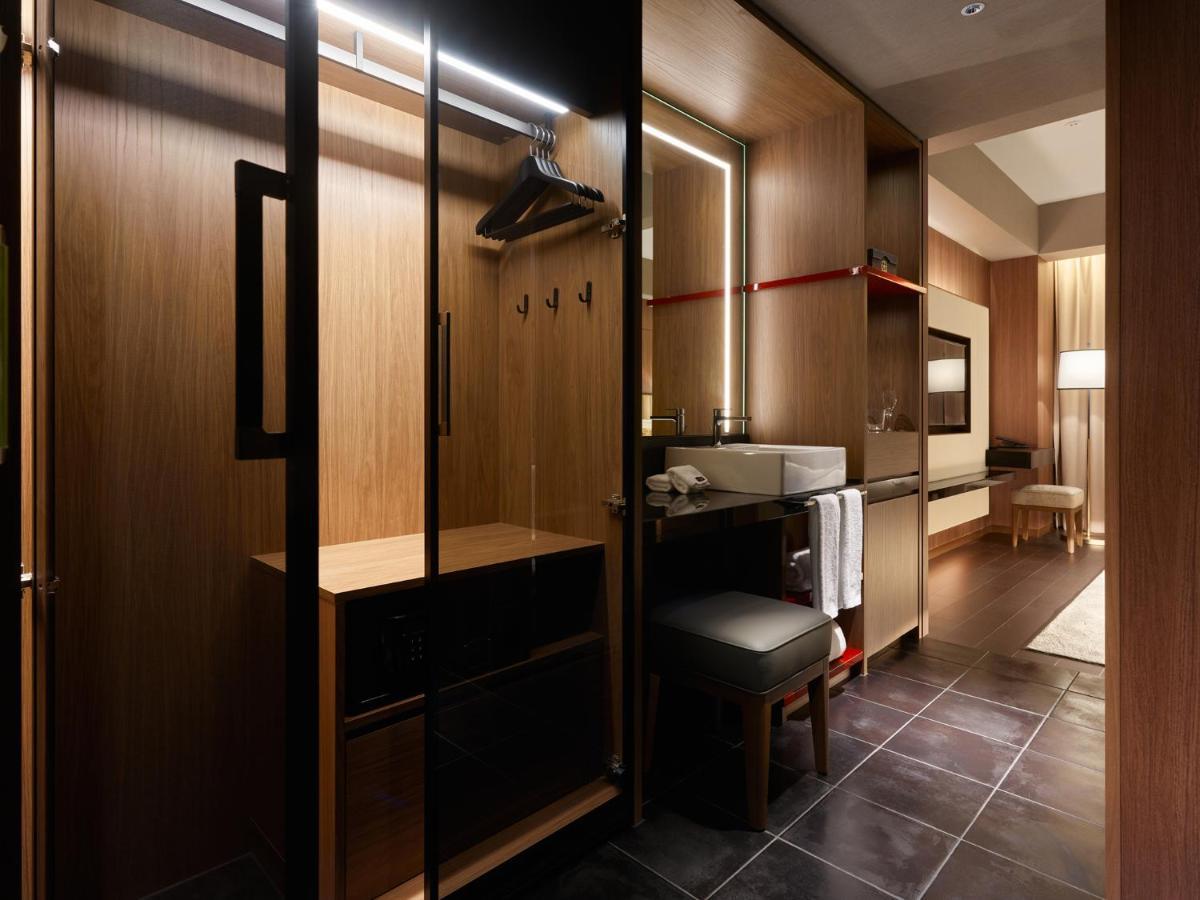 Mitsui Garden Hotel Roppongi Tokyo Premier Εξωτερικό φωτογραφία The photo depicts a modern and stylish hotel room's closet area. It features wooden cabinetry with a sleek finish, including mirrored doors. Inside, there are hangers for clothing and hooks mounted on the wall. A small bench or chair is positioned ne