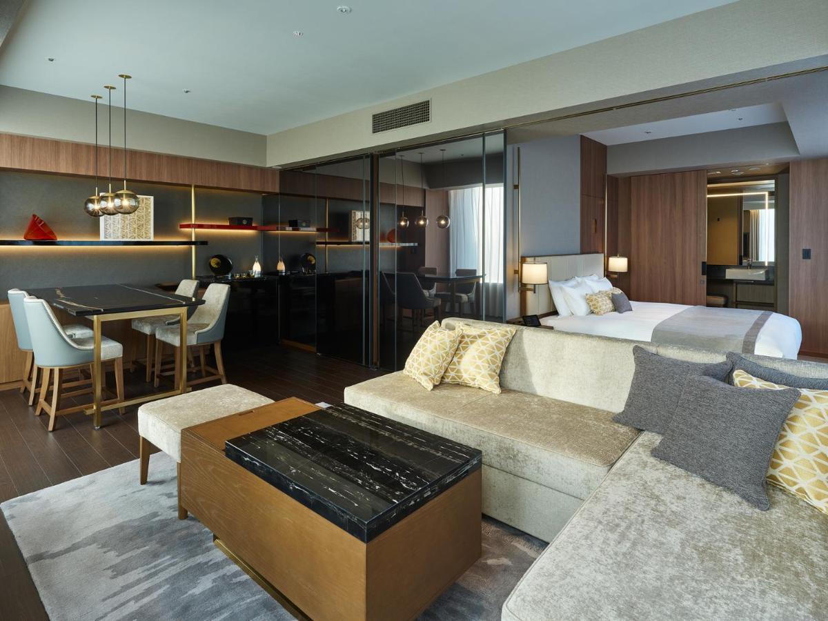 Mitsui Garden Hotel Roppongi Tokyo Premier Εξωτερικό φωτογραφία The image shows a modern hotel room or suite that features a contemporary design. Key elements include:

- A comfortable seating area with a light-colored sofa and a stylish coffee table.
- A dining area with a table and chairs, suggesting space for 