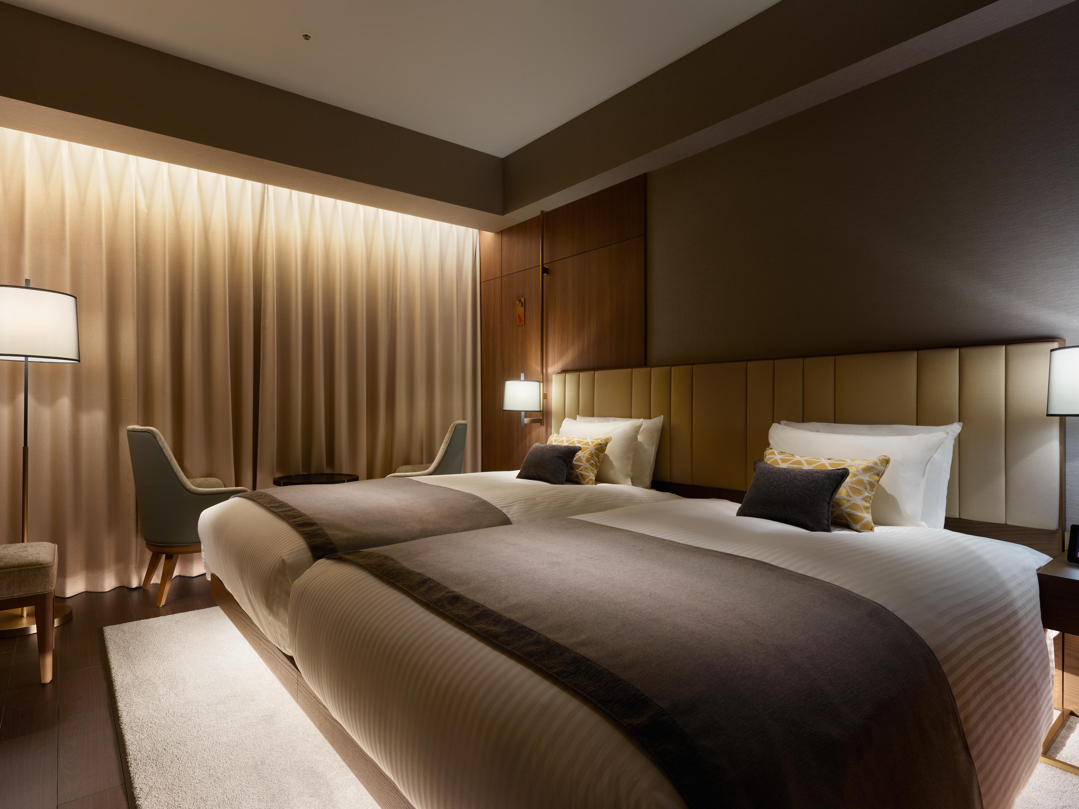 Mitsui Garden Hotel Roppongi Tokyo Premier Εξωτερικό φωτογραφία The photo shows a modern hotel room featuring two twin beds with elegant bedding. The room is adorned with soft, neutral tones and has a warm ambiance created by subtle lighting. A pair of bedside lamps provide additional light, and there is a cozy c
