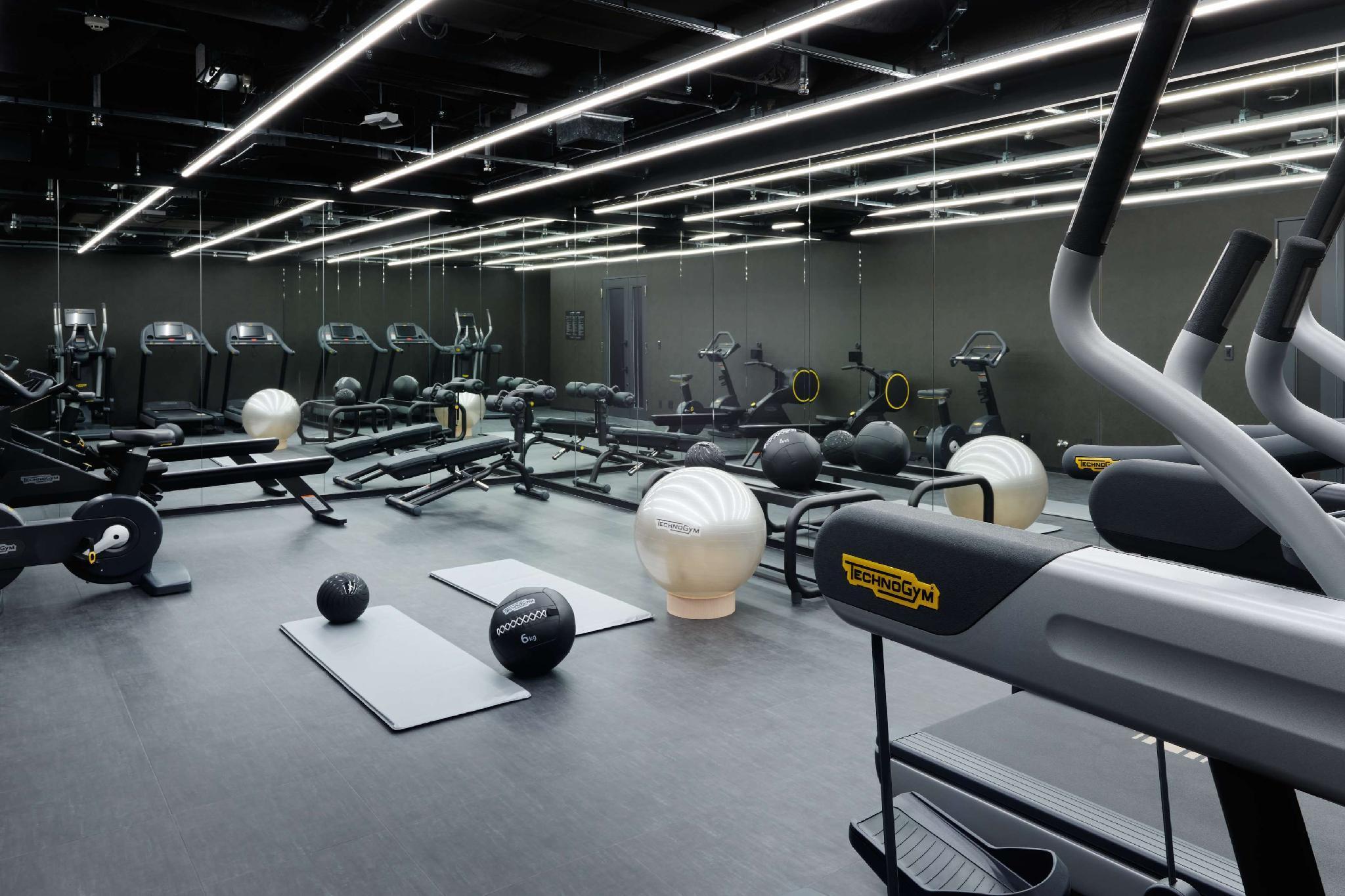 Mitsui Garden Hotel Roppongi Tokyo Premier Εξωτερικό φωτογραφία The photo shows a modern gym interior. The space features various exercise equipment, including cardio machines like treadmills and elliptical trainers, weight machines, and free weights. There are also exercise mats and fitness balls scattered throu